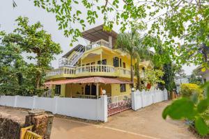 a yellow house with a white fence in front of it at The Yellow House By Leela in Patnem