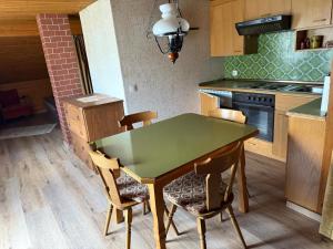 a kitchen with a green table and chairs at Knusperhäuschen Nassfeld in Sonnenalpe Nassfeld +8 photos