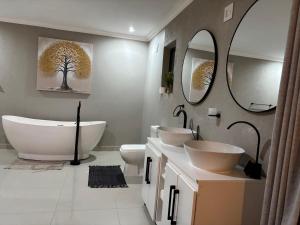 a bathroom with two sinks and two mirrors at Amahle Guesthouse Bush in Dwarsloop +19 photos
