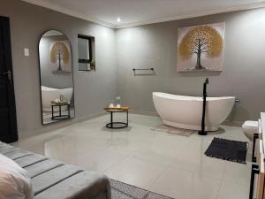 a bathroom with a bath tub and two mirrors at Amahle Guesthouse Bush in Dwarsloop