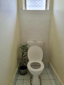a bathroom with a toilet and a potted plant at Panatina Hilltop Downstairs Unit in Honiara
