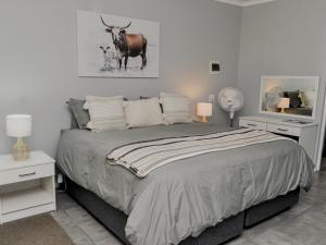 a bedroom with a bed with a cow on the wall at River Bend Farm in Lidgetton