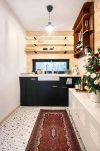a kitchen with black cabinets and a sink and a rug at Nastawka Cottage Creativity and Regeneration in Raciechowice +22 photos