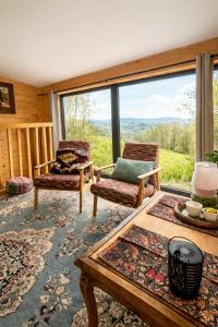 a living room with two chairs and a table and a large window at Nastawka Cottage Creativity and Regeneration in Raciechowice