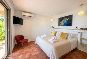 a bedroom with a white bed and a red chair at Hôtel U San Daniellu villas et chambres in Saint-Florent