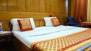a bedroom with a large bed with pillows on it at Hotel Ech Aar, Kargil in Kargil