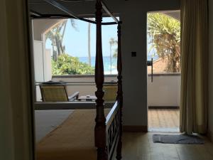 a bedroom with a bed and a large window at Sri Gemunu Beach Resort in Unawatuna