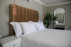 a bedroom with a bed with white pillows and a mirror at Amahle Guesthouse Bush in Dwarsloop