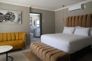 a bedroom with a large bed and a yellow couch at Amahle Guesthouse Bush in Dwarsloop