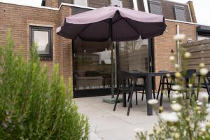 a table and chairs under an umbrella on a patio at Heggerank 5a in Nieuwvliet