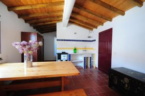 a kitchen with a wooden table with flowers on it at Hortas de Baixo, Luz de Tavira in Tavira