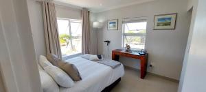 a bedroom with a bed and a desk and a window at Agulhas Splendour in Agulhas