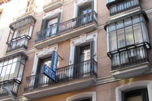 a building with balconies and a blue sign on it at Hostal Prim in Madrid