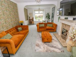 a living room with orange couches and a fireplace at Burry House in Swansea