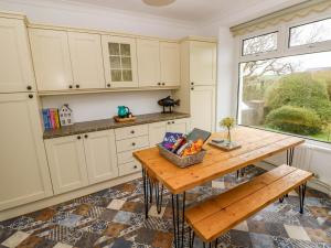 a kitchen with white cabinets and a wooden table at Burry House in Swansea
