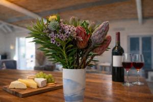 a vase of flowers on a table with wine glasses at BlueSky Arniston Boutique Guesthouse in Arniston