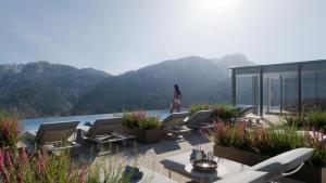 a woman walking on a patio with chairs and water at Hotel Majestic - Unique Spa Resort in Brunico +93 photos