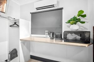 a kitchen with a counter with a microwave on a shelf at Darwin CBD Escape-Cosy and Central in Darwin