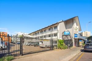 a building with a fence next to a parking lot at Darwin CBD Escape-Cosy and Central in Darwin