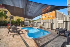 a patio with a swimming pool with chairs and a canopy at Darwin CBD Escape-Cosy and Central in Darwin