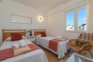 a bedroom with two beds and a chair and a window at Hawaii in Jávea