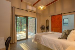 a bedroom with a bed and a sliding glass door at Spoorzicht in Marloth Park +24 photos