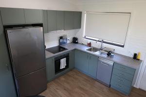 a small kitchen with a sink and a refrigerator at Rivergums Cottage in Dubbo