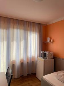 a room with a white curtain and a microwave at 2-Rent Group Hostel Rooms AUB162 in Munich