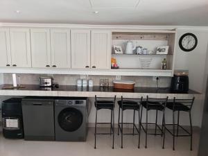 a kitchen with a counter with a dishwasher and stools at Agulhas Splendour in Agulhas +33 photos