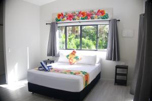 a bedroom with a white bed with a window at Purotu Villas in Avarua