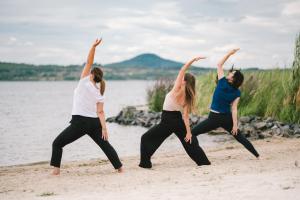 a group of three women doing yoga on the beach at Insel der Sinne Naturhotel in Görlitz