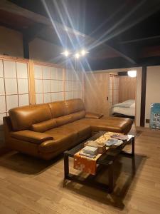 a living room with a brown leather couch and a table at 陽月 Yo-Getsu in Yamaga