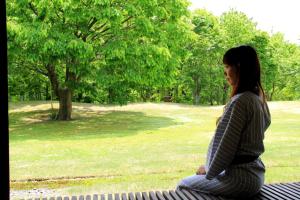 a woman sitting on a bench in a park at Bunanoyado Koase in Aga