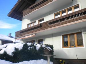 a white house with snow in front of it at Ferienwohnung Nussbaumer in Niedernsill