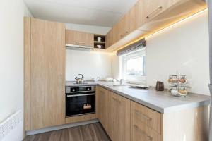 a kitchen with wooden cabinets and a black oven at NATURAMA Brombachsee Tinyhaushotel in Pleinfeld
