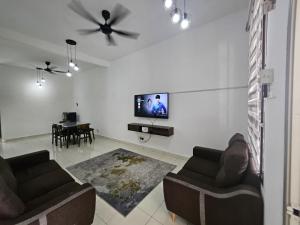 a living room with two couches and a flat screen tv at Razumi's Homestay 2 in Arau