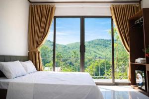 a bedroom with a large window with a mountain view at Thành An Homestay in Hòa Bình
