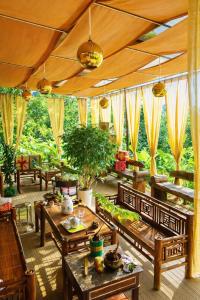 a living room with tables and chairs and trees at Thành An Homestay in Hòa Bình