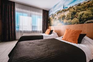 two beds in a room with a painting on the wall at Hotel Pax in Luxembourg