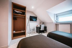 a bedroom with two beds and a window and a desk at Hotel Pax in Luxembourg
