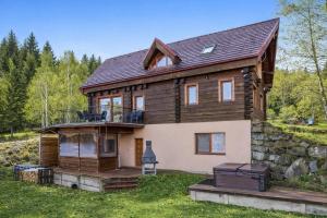 a large wooden house with a stone wall at ZRUB BINDT in Hnilčík