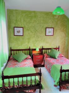 two beds in a bedroom with green walls at Casa Rural la Muralla in Talamanca de Jarama