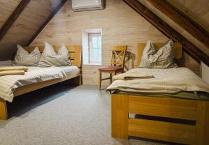 a attic bedroom with two beds and a chair at Penzion Festung in Petrovice
