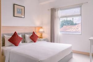 a bedroom with a large white bed with red pillows at Orbit House in Bandung