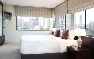 a bedroom with a large white bed with a large window at The Quarter Saladaeng by UHG in Bangkok