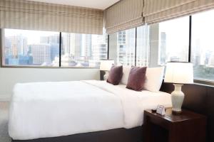 a white bed in a room with a large window at The Quarter Saladaeng by UHG in Bangkok