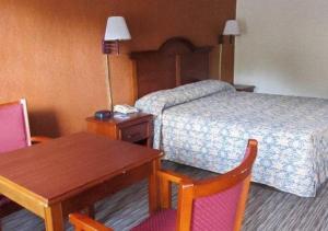 een hotelkamer met een bed, een tafel en stoelen bij Rodeway Inn in Forsyth