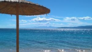 a straw umbrella on a beach with the ocean at Dodis Village in Platanias