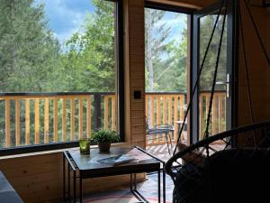 a screened in porch with a table and a window at Apusenity Resort I Piscină Interioară & Cabane în Natură in Cluj-Napoca