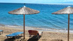two chairs and umbrellas on a beach with the ocean at Dodis Village in Platanias